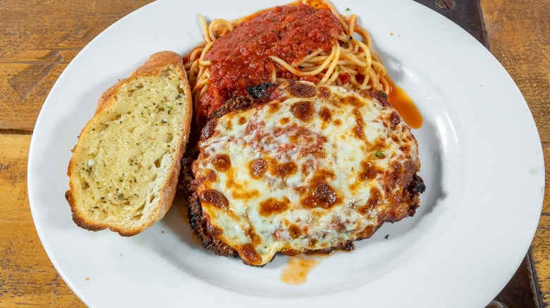Luca's chicken parm on a plate with garlic bread and spaghetti marinara