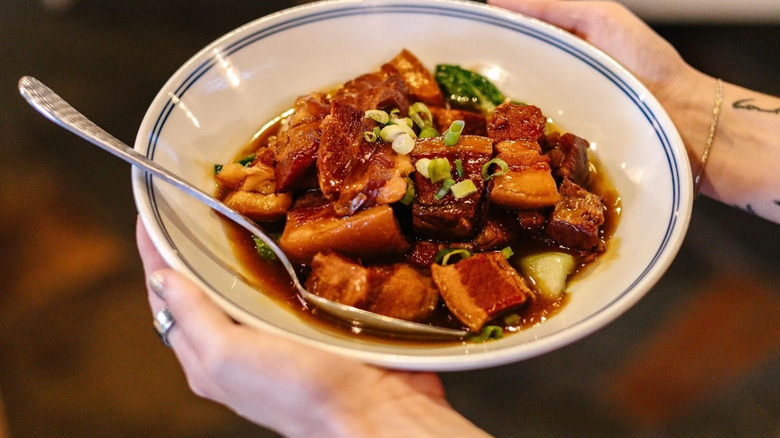 A person holding a bowl of pork belly at Petals of a Peony