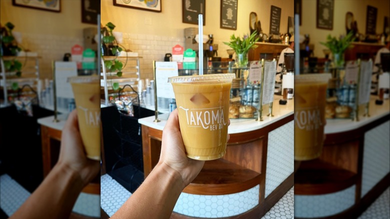 Person holding an iced coffee in front of the counter area at Takoma Beverage Company