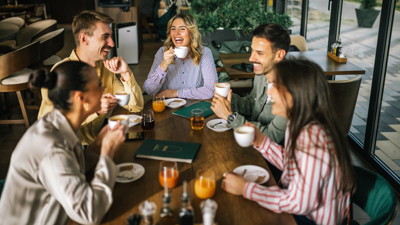 Group of friends talking and laughing together at a coffee shop