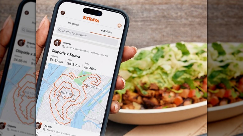 Hand holding phone with Strava app pulled up, chipotle bowl in background.