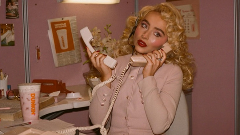 Sabrina Carpenter with Dunkin' signature drink in pink office.