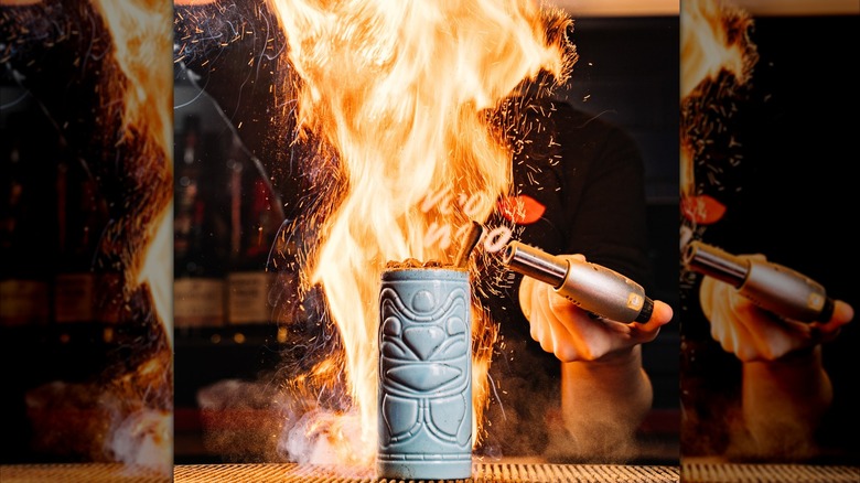 A tiki cocktail with flames on the top