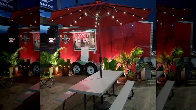 Beau's Bayou Smokehouse food truck set up with potted plants and patio tables decorated with string lights