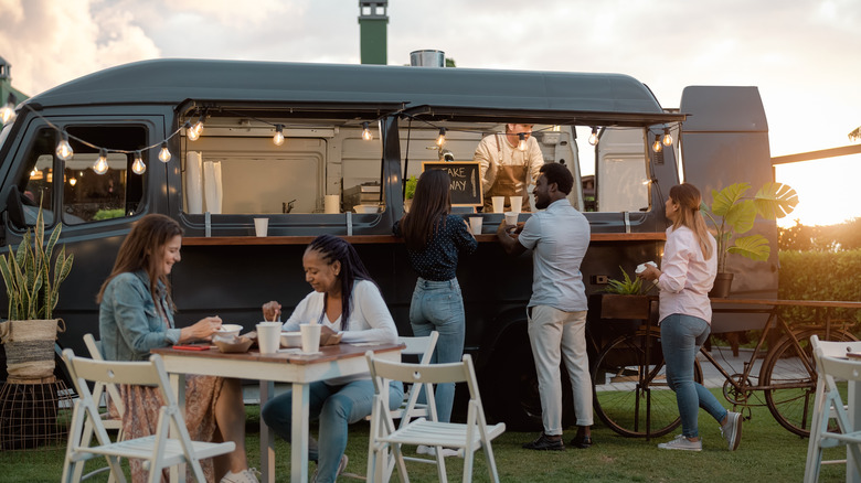 People ordering from and eating outside a food truck