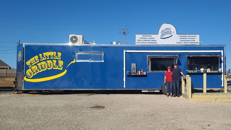 Two people standing in front of the blue Little Griddle truck