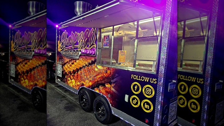 The purple exterior of Sharp BBQ food truck lit up at night