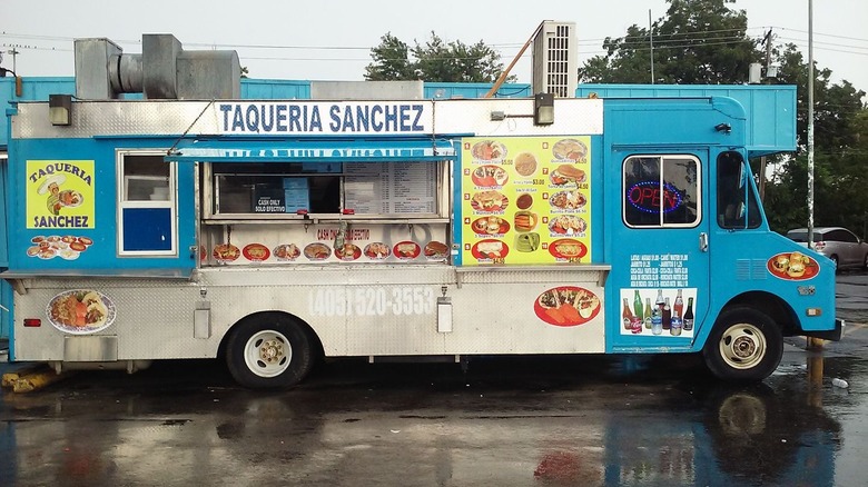 The blue exterior of Taqueria Sanchez parked on a wet street