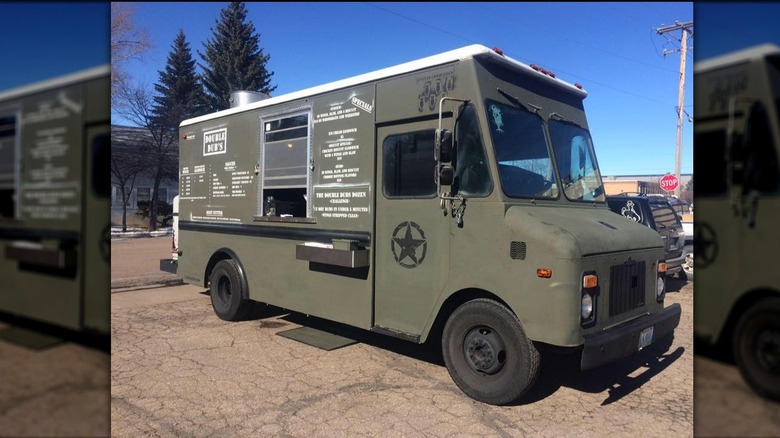 The khaki green Double Dubs food truck parked in a lot with blue sky in the background