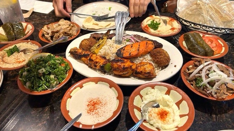 Assorted Mediterranean platters and dishes including hummus, kebabs, and stuffed grape leaves with pita bread at Makarios Kabobs & Grill