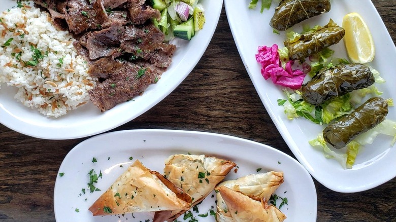 Platter of gyros with rice, platter of dolmades, and platter of spanakopita from Turkish Delight