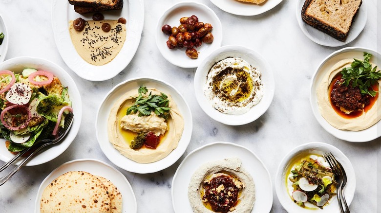 White table of assorted mezze, including hummus, pita, baba ghanoush, and olives at Bavel