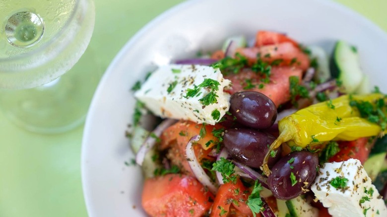 greek salad and bowl with wine glass