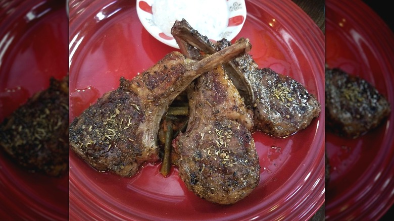 Dry aged lamb chops with a yogurt-based dipping sauce on a red plate at Istanbul Hawaii