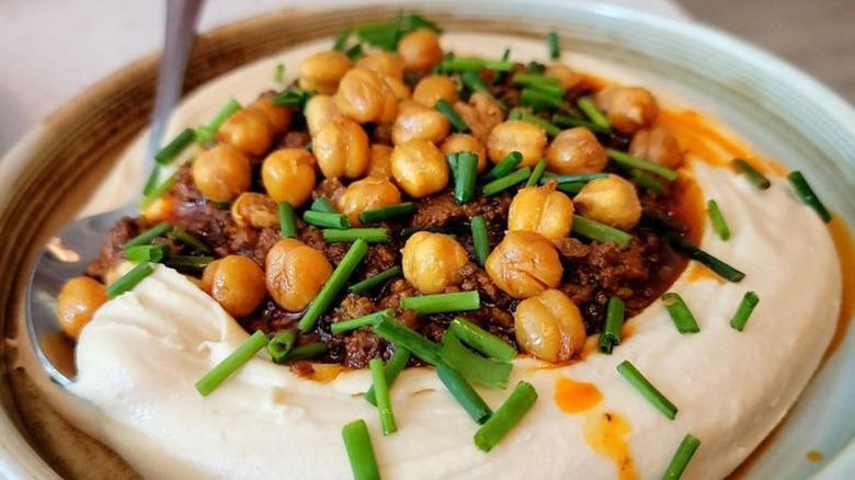 Fried chicken hummus on a tan, earthenware plate at Shaya