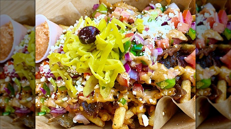 Street cart fries garnished with pepperoncinis and olives at Spitz