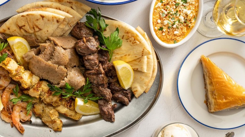 Gyro platter with pita and a serving of baklava on a white plate with blue rim at Meráki Greek Grill