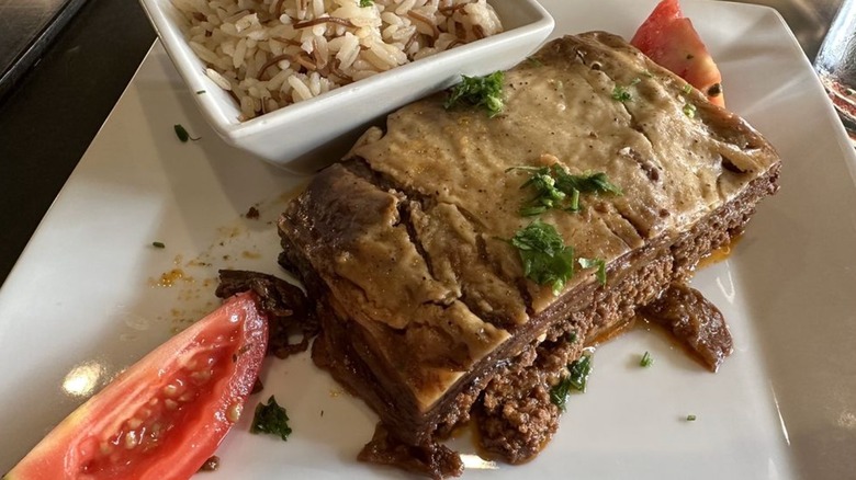 Moussaka with rice and tomatoes on a square white plate at Norma's Eastern Mediterranean Cuisine