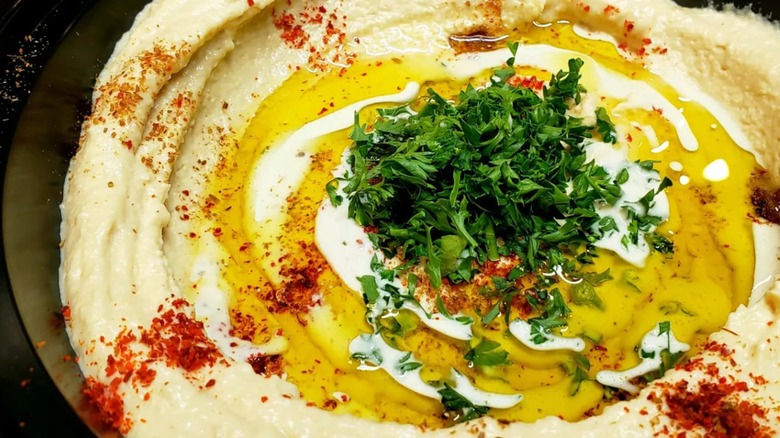 Close up of creamy hummus garnished with parsley, olive oil, and paprika at Cafe Rakka