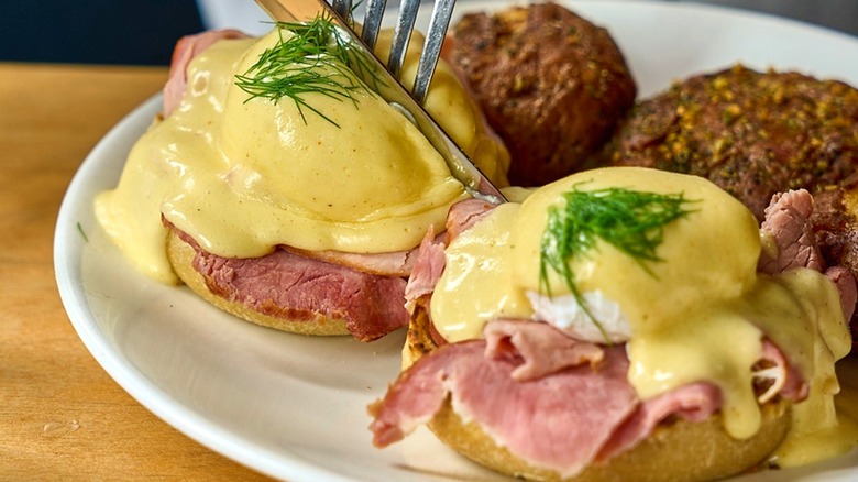 Eggs Benedict with lemon hollandaise on a white plate at Lola
