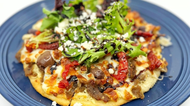 Greek pita pizza on a blue plate at Sweet Zoey Mediterranean