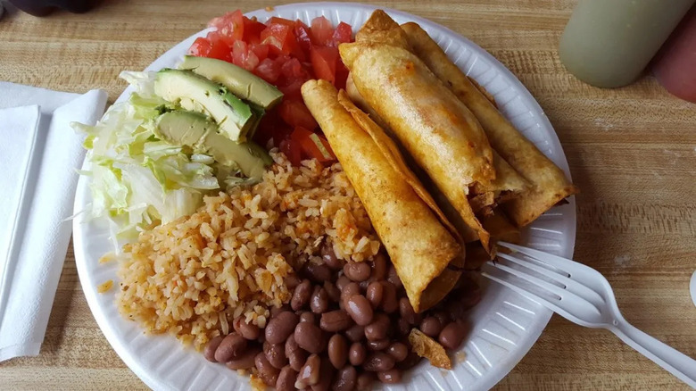 A plate of flautas with beans and rice at Tacos La Rosa