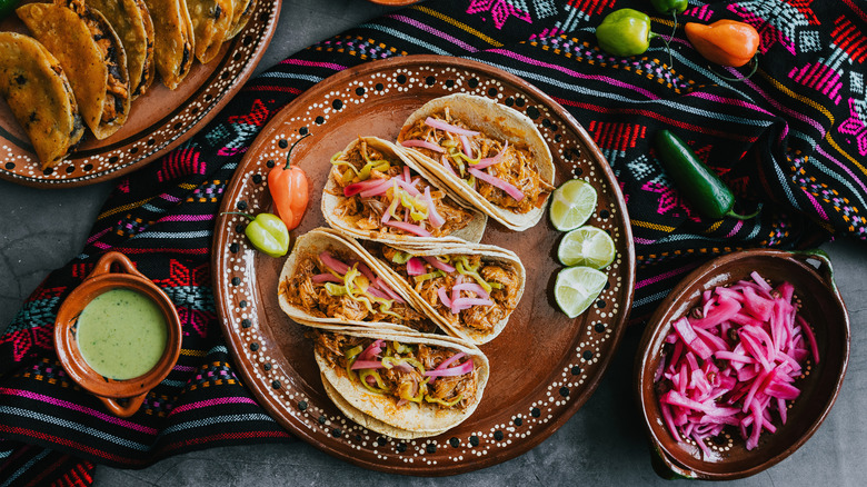 A plate of Mexican tacos on a table with condiments