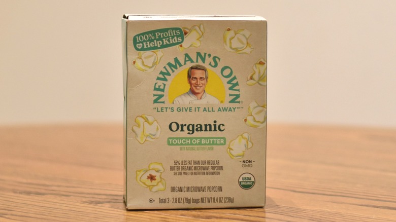 A box of Newman's Own popcorn is on a wooden table.