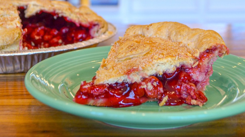 Slice of fresh cherry pie on a green plate