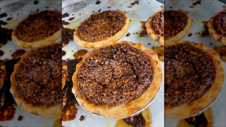 Several whole chocolate pecan bourbon pies on a baking sheet