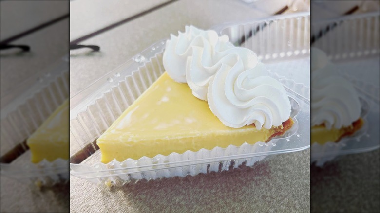 Slice of key lime pie with whipped cream in a plastic to-go container