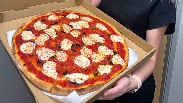 A person holding a margherita pizza from Saverio's Pizzeria in Alaska