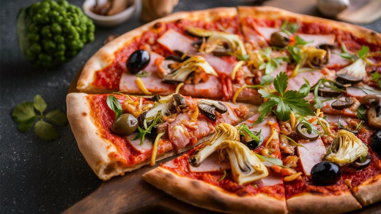 A pizza  with ham, artichokes, and olives