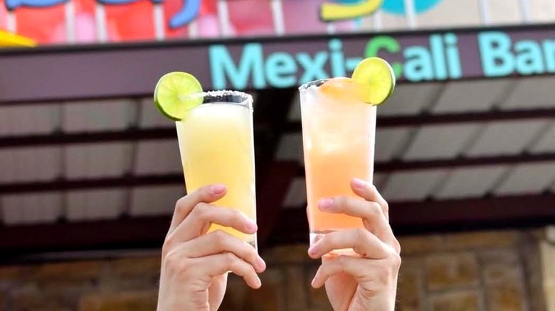 Margarita glasses clink in the air outside Baja Grill