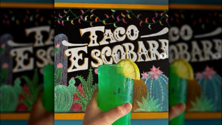 A green margarita in front of a Taco Escobarr sign