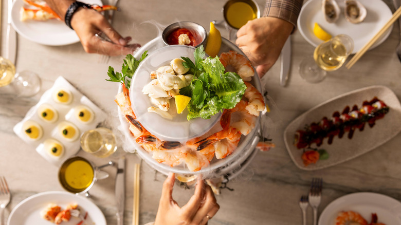 Hands grabbing from a seafood tower