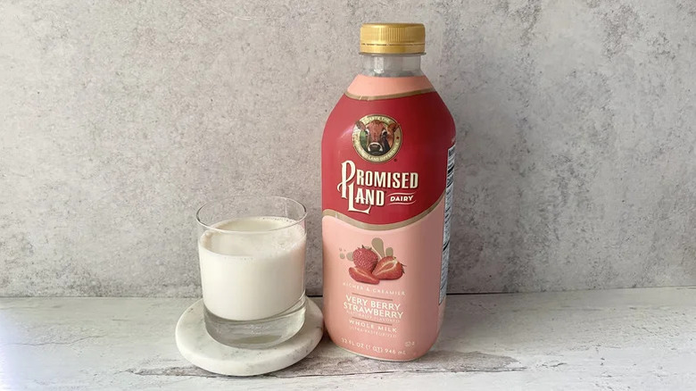 A bottle and glass of Promised Land Very Berry Strawberry Whole Milk