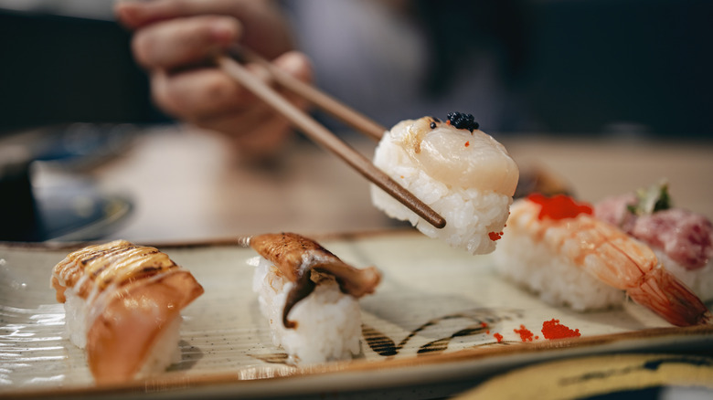 Hand picking up a sushi roll with chopsticks