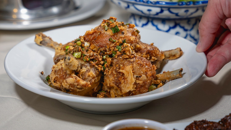A person holding a bowl of Thai-style chicken at Lotus of Siam