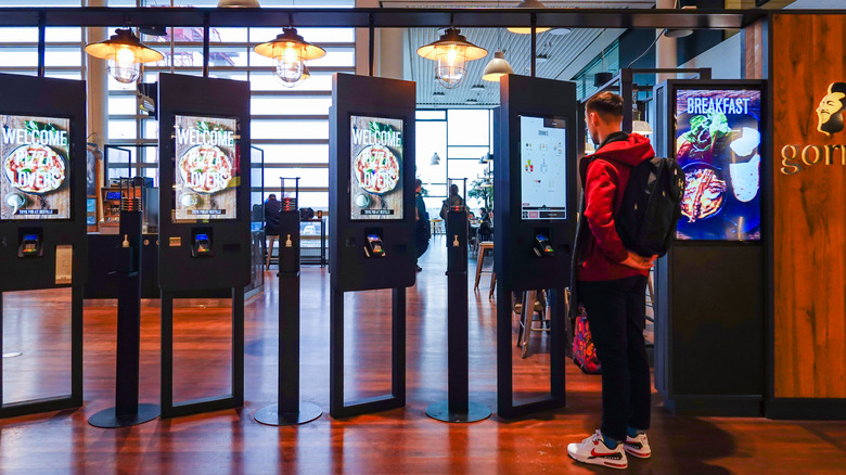Man ordering from kiosk in fast food restaurant