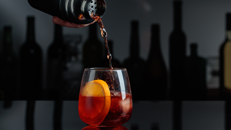 hand pouring a Negroni from a cocktail shaker