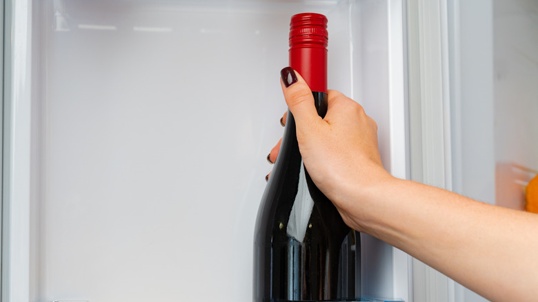 Female hand removing sweet vermouth from a fridge