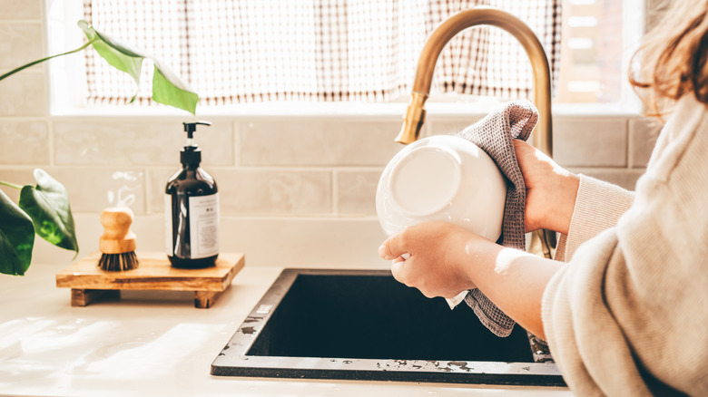 Woman drying dishes at farmhouse-style sink