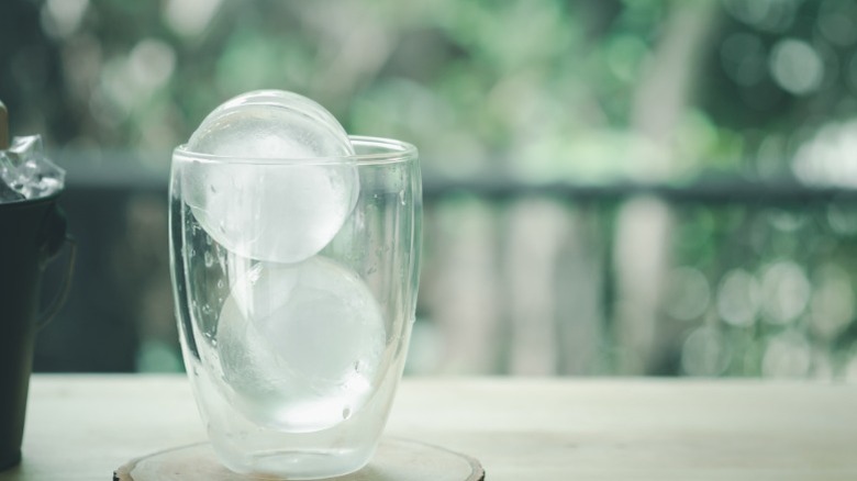 Two ice spheres in a short cocktail glass with no liquid in it yet.