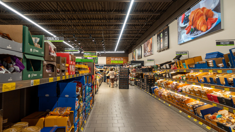 Customers shopping in Aldi bread and snacks aisles.