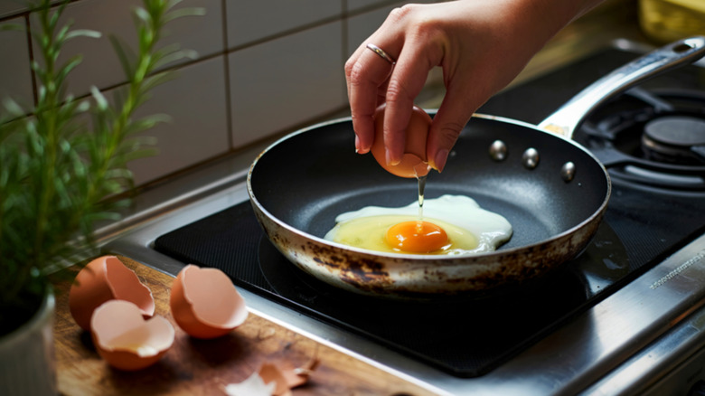 Hand cracking an egg into a nonstick pan.