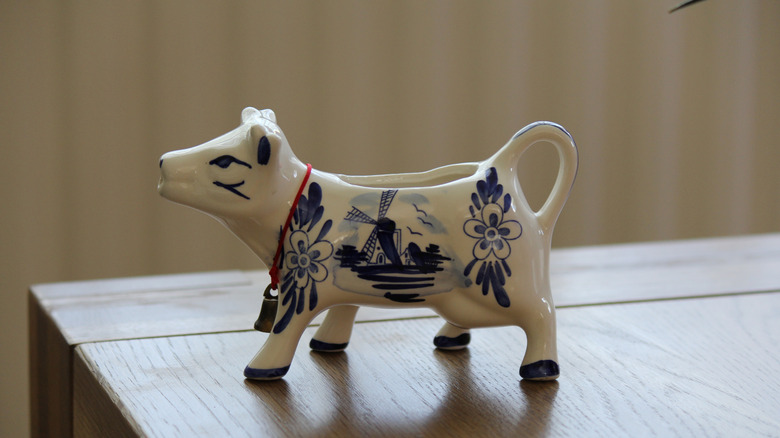 A blue and white cow creamer with a windmill painted on its side