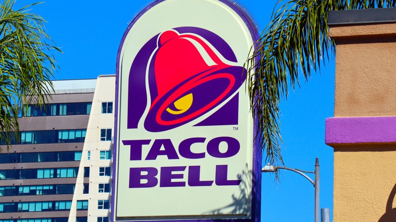 A Taco Bell sign next to a palm frond