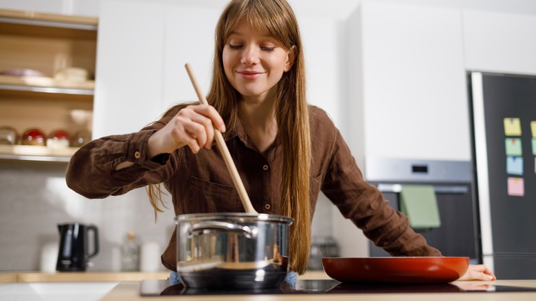Woman stirring pot with a wooden spoon.