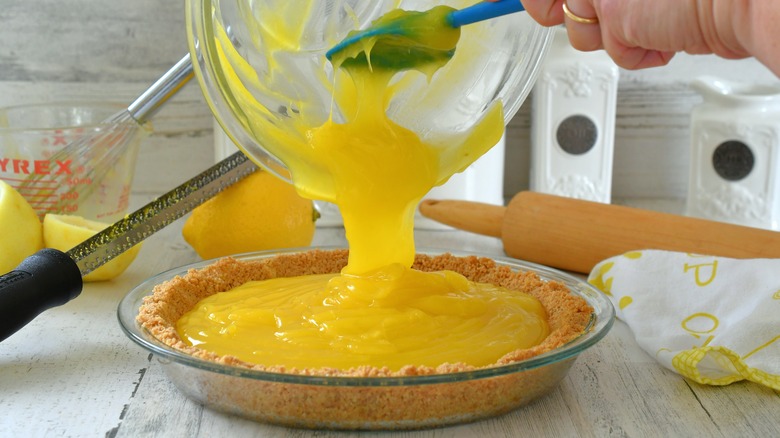 Pouring lemon pie filling into graham cracker crust